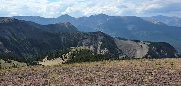 Panoramic view of rugged mountains and valleys under a partly cloudy sky.